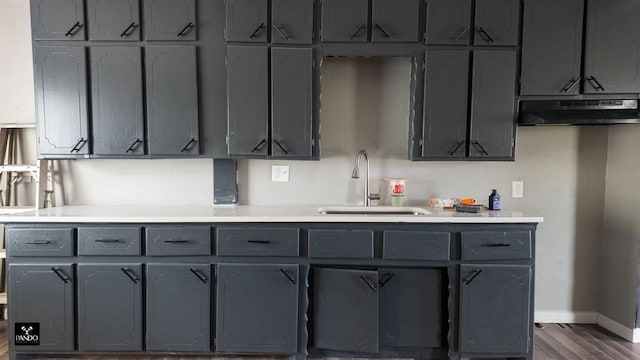 313 W Texas Ave, Anadarko, OK 73005 - kitchen featuring under cabinet range hood, gray cabinetry, light countertops, and dark wood-type flooring