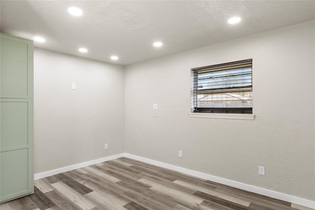 spare room featuring wood-type flooring and a textured ceiling