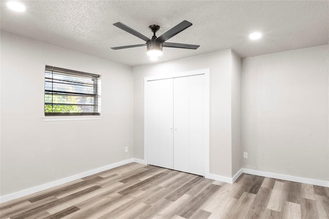 unfurnished bedroom featuring a textured ceiling, light hardwood / wood-style flooring, a closet, and ceiling fan