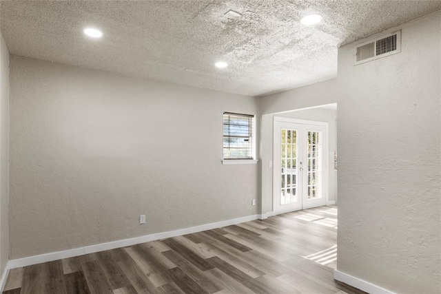 empty room featuring hardwood / wood-style flooring, french doors, and a textured ceiling