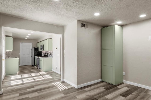 interior space featuring sink, light hardwood / wood-style floors, and a textured ceiling