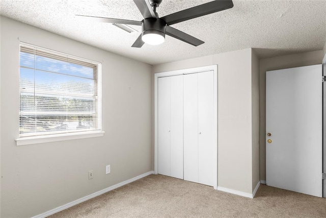 unfurnished bedroom featuring ceiling fan, light colored carpet, multiple windows, and a closet