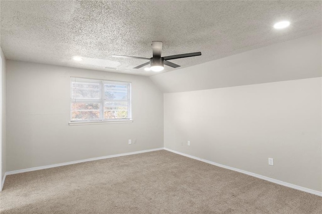 carpeted empty room with ceiling fan, a textured ceiling, and lofted ceiling