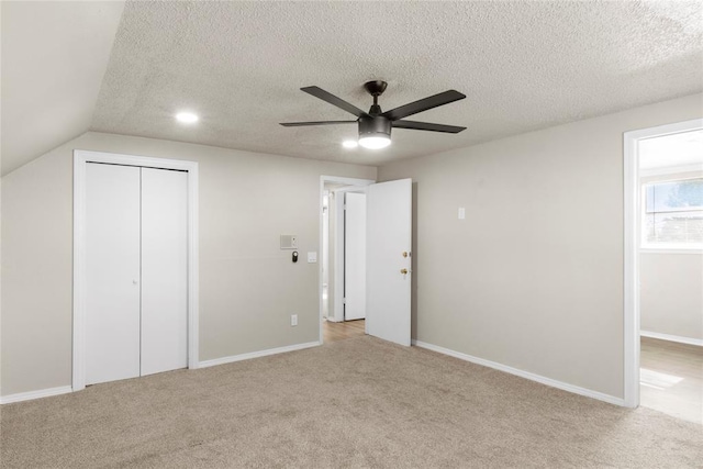 unfurnished bedroom with a closet, ceiling fan, vaulted ceiling, and light carpet