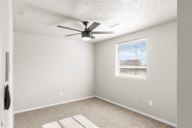 empty room featuring a textured ceiling, light colored carpet, and ceiling fan