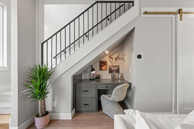 interior space featuring built in desk, a barn door, and light hardwood / wood-style floors