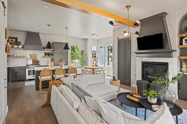 living room with a large fireplace, beamed ceiling, and dark hardwood / wood-style flooring