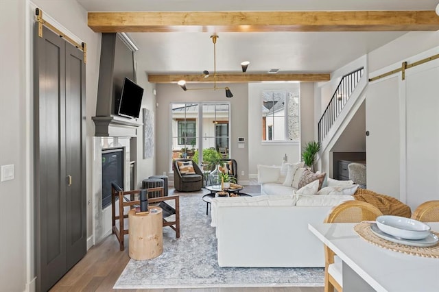 living room featuring beam ceiling, a barn door, and light wood-type flooring