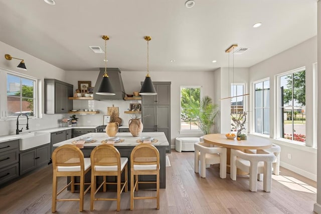 kitchen with sink, a kitchen island, decorative light fixtures, and gray cabinets