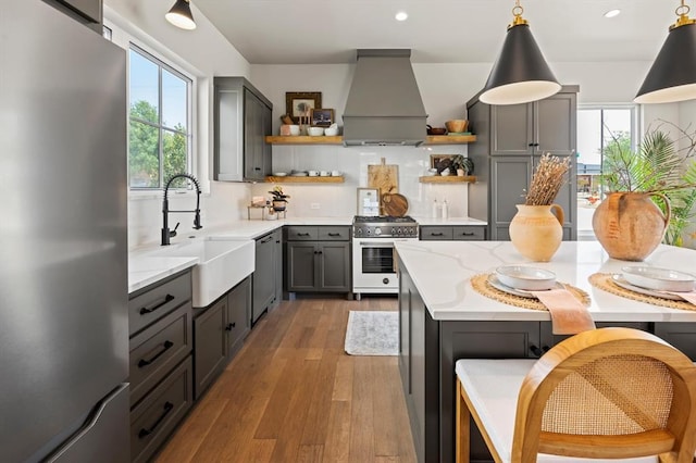 kitchen with appliances with stainless steel finishes, sink, hanging light fixtures, gray cabinets, and custom range hood