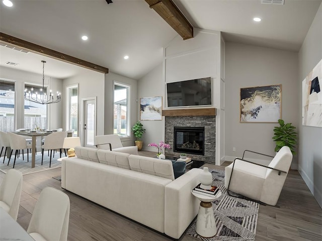 living room with hardwood / wood-style flooring, a stone fireplace, a chandelier, and vaulted ceiling with beams