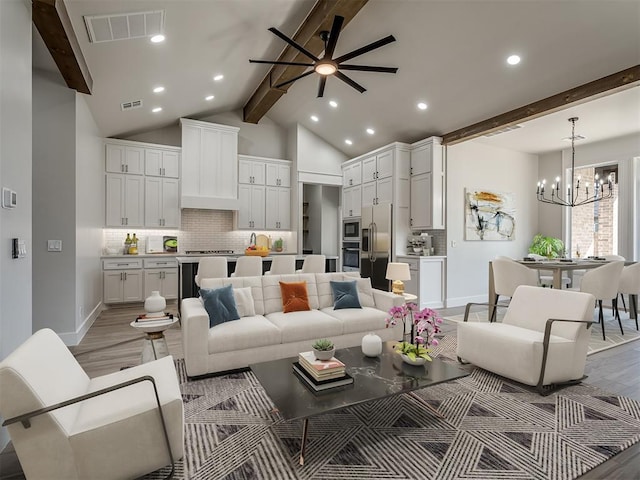 living room featuring vaulted ceiling with beams, ceiling fan with notable chandelier, and light hardwood / wood-style floors