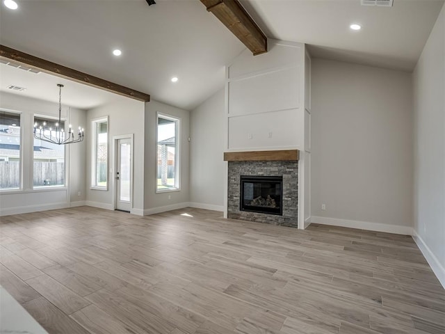 unfurnished living room with an inviting chandelier, a stone fireplace, lofted ceiling with beams, and light wood-type flooring