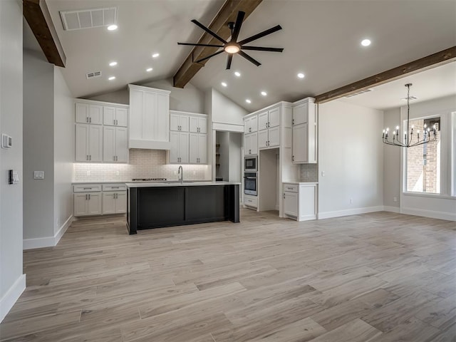 kitchen with a kitchen island with sink, custom range hood, white cabinets, ceiling fan with notable chandelier, and light wood-type flooring