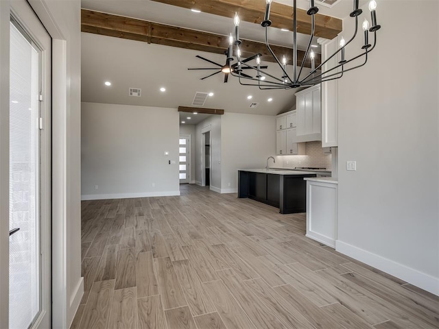 kitchen featuring white cabinetry, an island with sink, sink, backsplash, and light hardwood / wood-style flooring