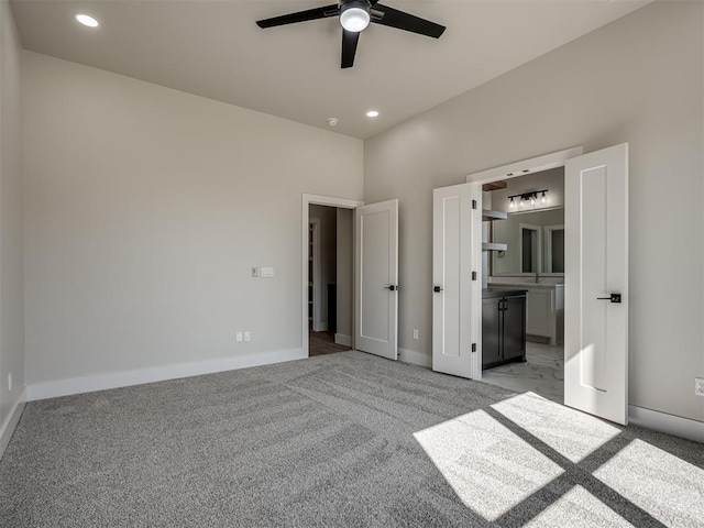 unfurnished bedroom featuring ensuite bathroom, light colored carpet, and ceiling fan