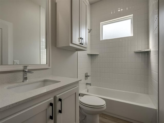 full bathroom with vanity, hardwood / wood-style flooring, toilet, and tiled shower / bath