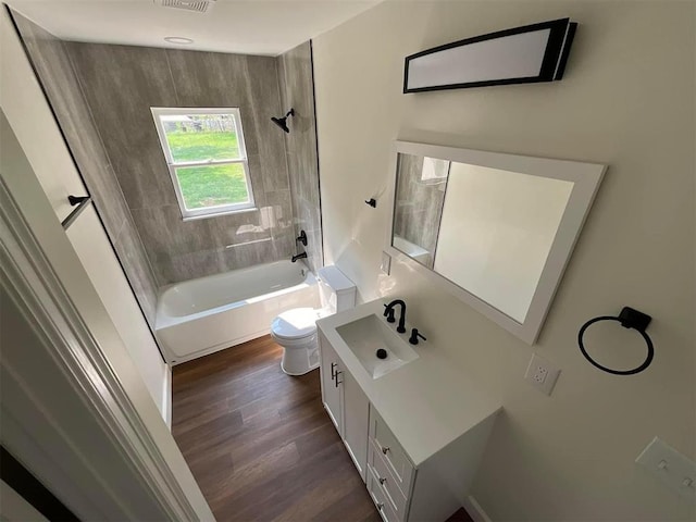 full bathroom featuring vanity, hardwood / wood-style floors, tiled shower / bath combo, and toilet