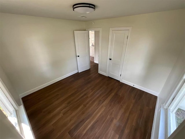 unfurnished bedroom with dark wood-type flooring and a closet