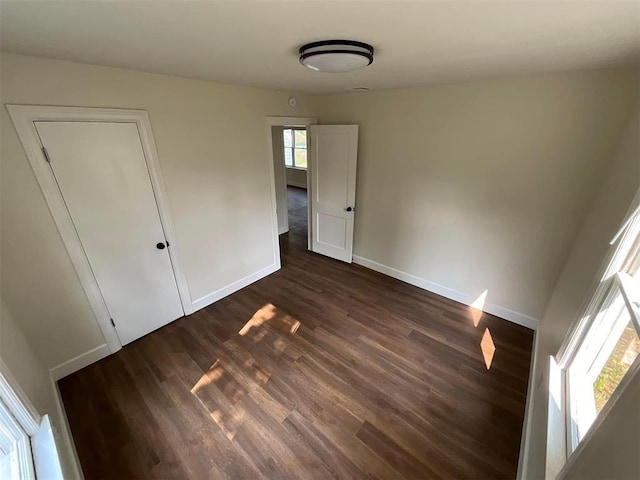 unfurnished bedroom with dark hardwood / wood-style flooring and a closet