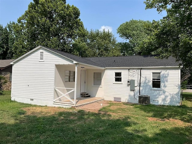 rear view of property with central AC and a lawn