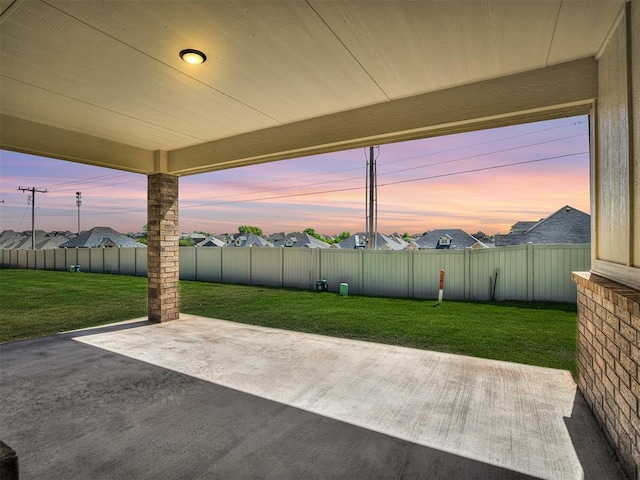 patio terrace at dusk featuring a lawn