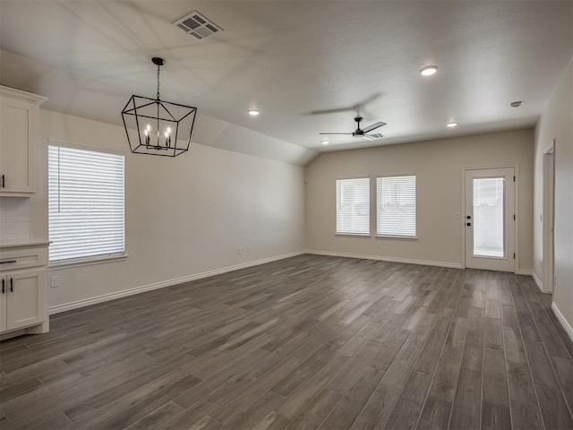 unfurnished living room with lofted ceiling, ceiling fan with notable chandelier, and dark hardwood / wood-style flooring