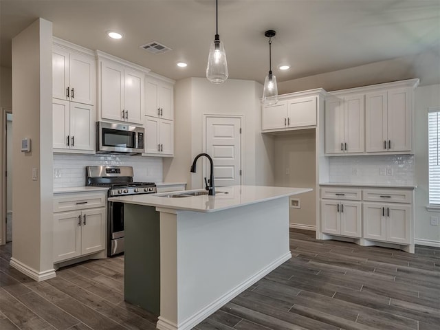 kitchen featuring stainless steel appliances, white cabinetry, sink, and pendant lighting