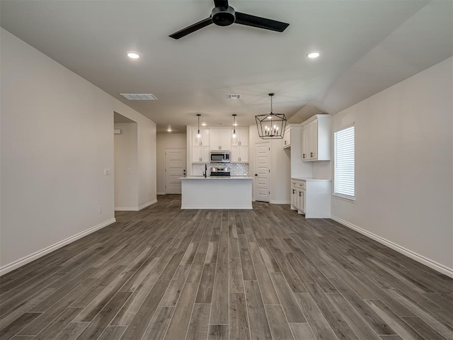 unfurnished living room with dark hardwood / wood-style flooring and ceiling fan with notable chandelier