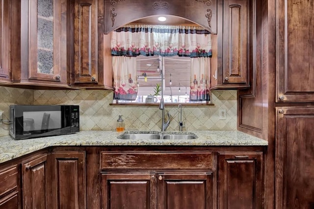 kitchen featuring sink, dark brown cabinets, tasteful backsplash, and light stone counters