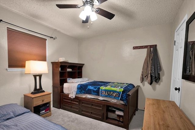 carpeted bedroom featuring ceiling fan and a textured ceiling