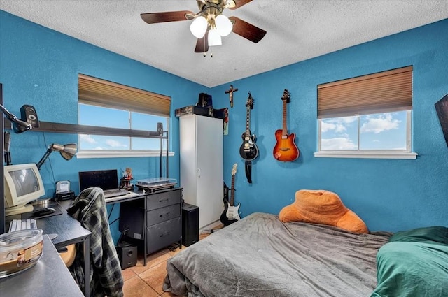 tiled bedroom with multiple windows, a textured ceiling, and ceiling fan