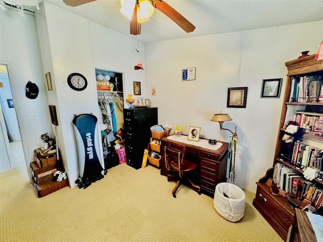 carpeted office space featuring ceiling fan and a textured ceiling