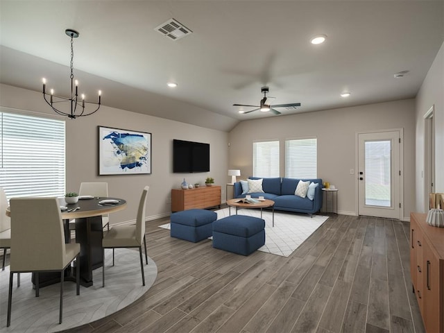 living area with ceiling fan with notable chandelier, baseboards, wood finished floors, and visible vents