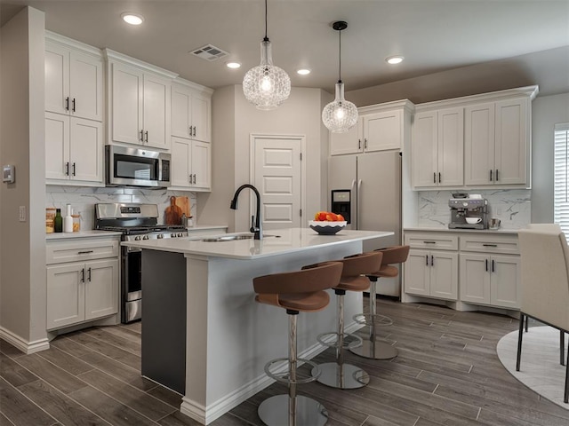 kitchen with dark wood finished floors, white cabinetry, stainless steel appliances, and a sink