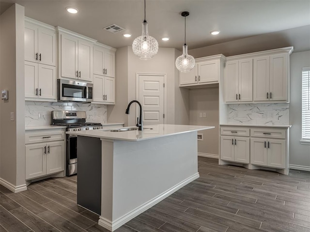 kitchen featuring white cabinets, dark wood-style floors, stainless steel appliances, a sink, and tasteful backsplash