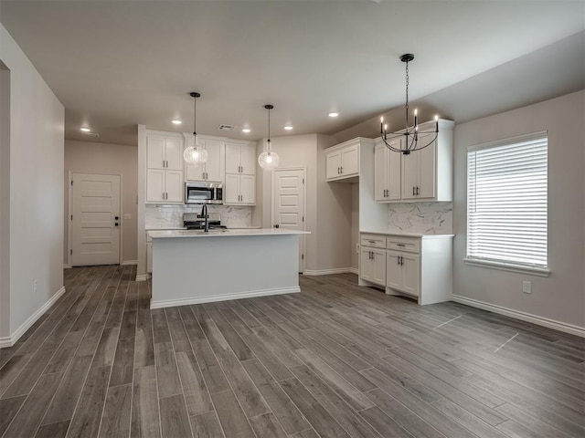 kitchen featuring stainless steel microwave, dark wood-style flooring, a notable chandelier, and tasteful backsplash