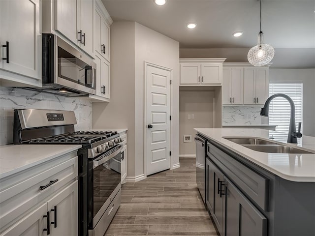 kitchen with appliances with stainless steel finishes, a sink, light wood finished floors, and recessed lighting