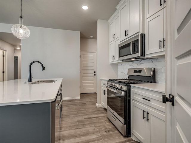 kitchen featuring stainless steel appliances, light countertops, a sink, light wood-type flooring, and tasteful backsplash