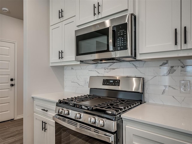 kitchen featuring backsplash, wood finished floors, white cabinetry, and appliances with stainless steel finishes