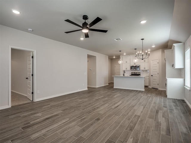 unfurnished living room featuring baseboards, visible vents, and dark wood-style floors