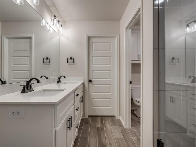 full bathroom with toilet, a sink, wood tiled floor, and double vanity