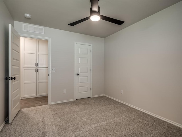 unfurnished bedroom with baseboards, a ceiling fan, visible vents, and carpet