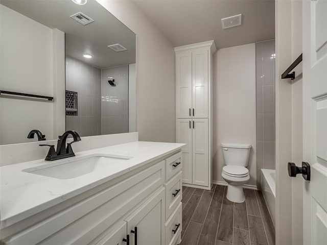 full bath featuring vanity, toilet, wood finish floors, and visible vents