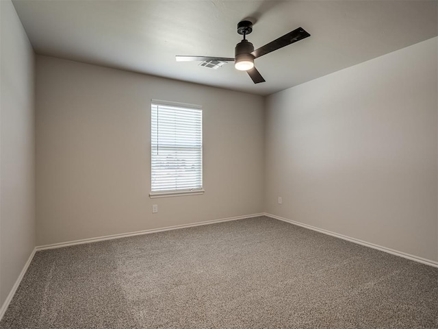 carpeted spare room with visible vents, a ceiling fan, and baseboards