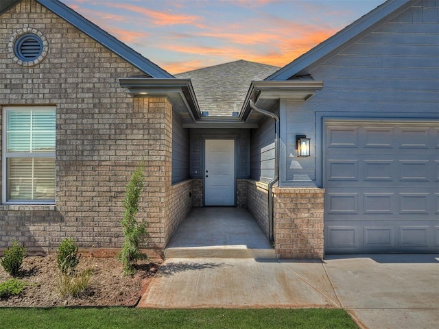 doorway to property with brick siding and a garage