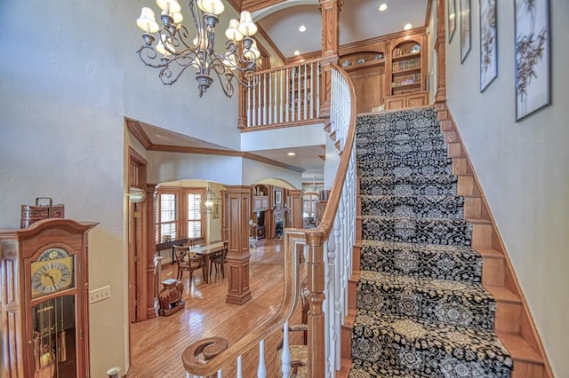 344 Millbrook Dr, Norman, OK 73072 - stairway featuring ornate columns, crown molding, a towering ceiling, and an inviting chandelier