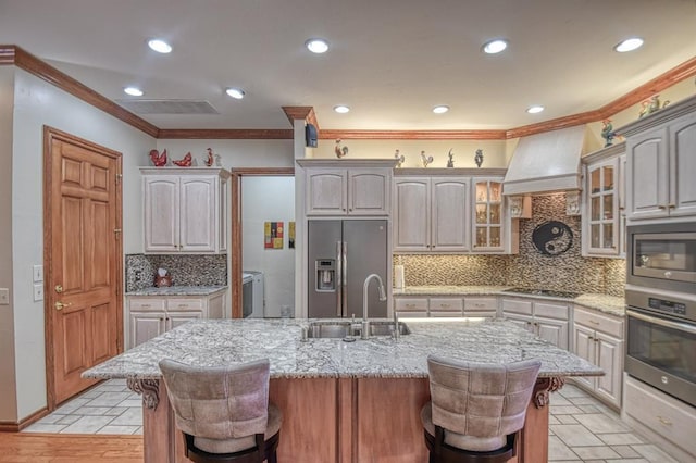 344 Millbrook Dr, Norman, OK 73072 - kitchen with a breakfast bar, sink, appliances with stainless steel finishes, custom range hood, and a kitchen island with sink