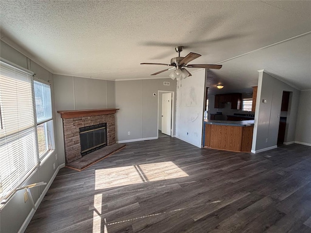 unfurnished living room with ceiling fan, plenty of natural light, dark hardwood / wood-style floors, and a fireplace