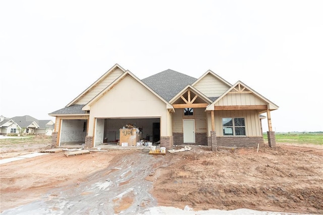 view of front of house with roof with shingles, a garage, brick siding, and board and batten siding